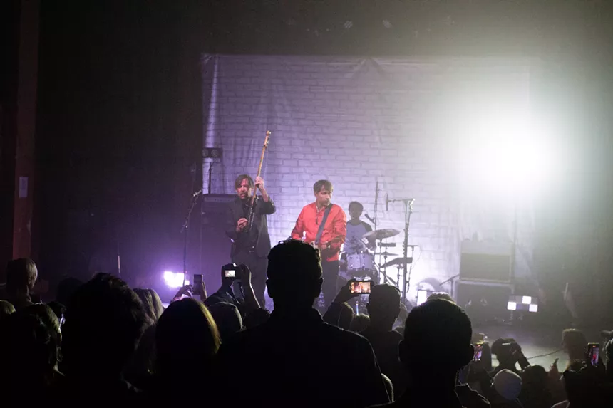 Three band members performing on a stage
