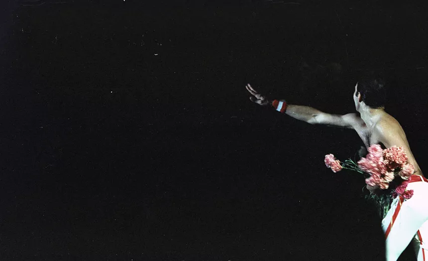 Freddie Mercury throws a bouquet of flowers to his fans.