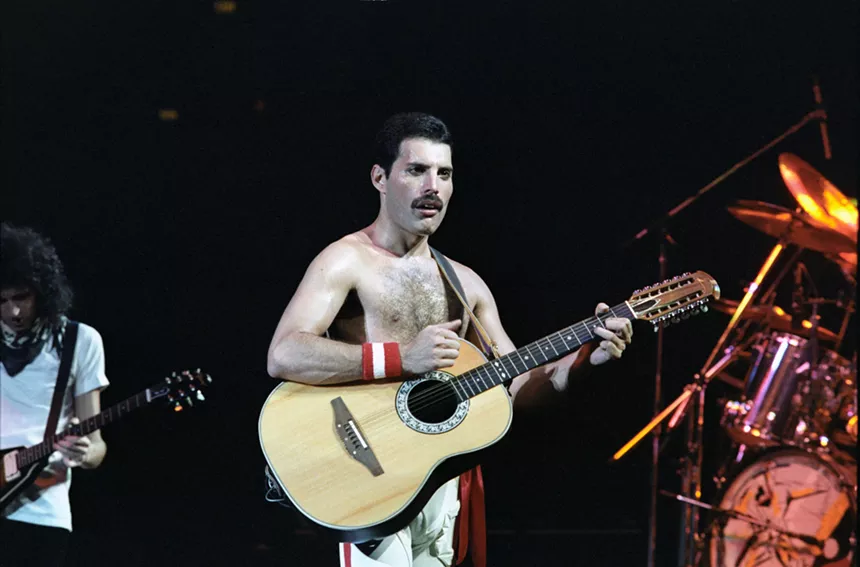 Freddie Mercury playing acoustic guitar