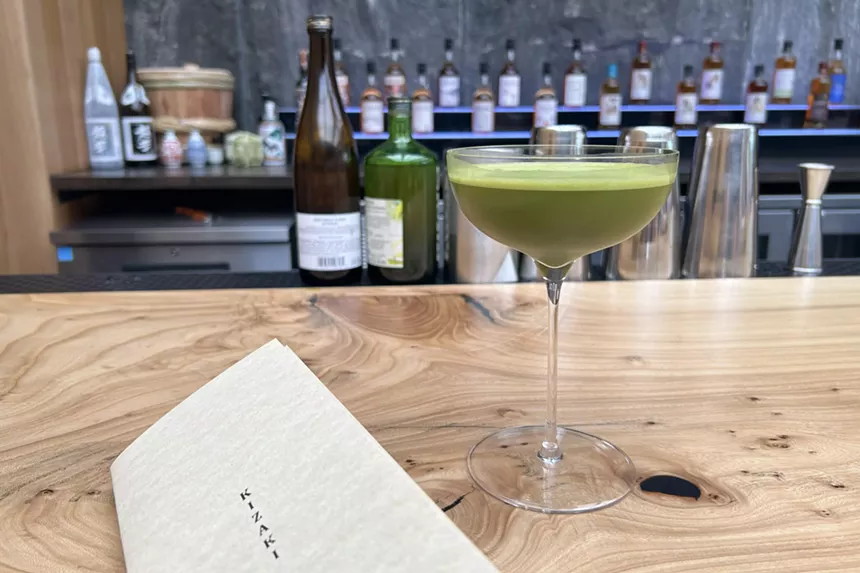A matcha martini resting on the sycamore wood bar within Denchu