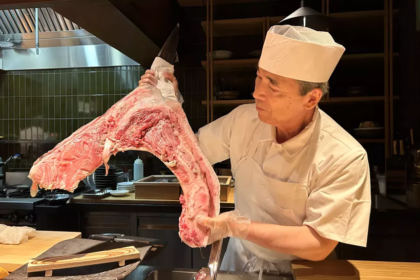 Chef Kizaki holding a large piece of cut tuna