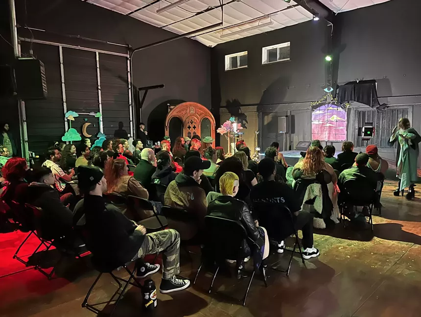 An audience sits down watching a performer on stage