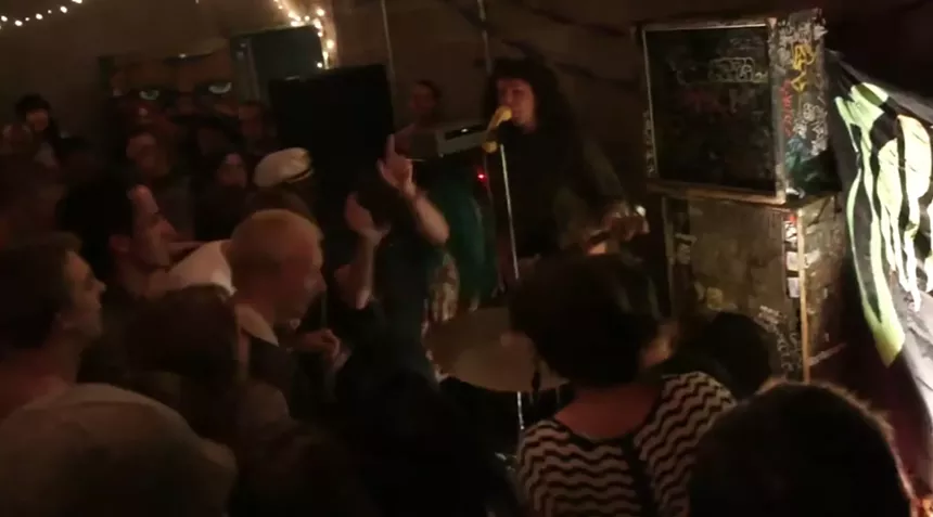 An enthusiastic and crowded audience watches as a band plays