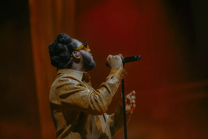 Leon Bridges on stage at Red Rocks with a red haze behind him.