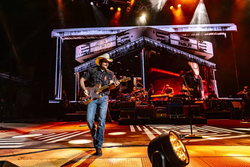 A photo showing Brad Paisley on stage at Red Rocks with stage lights and design behind him.