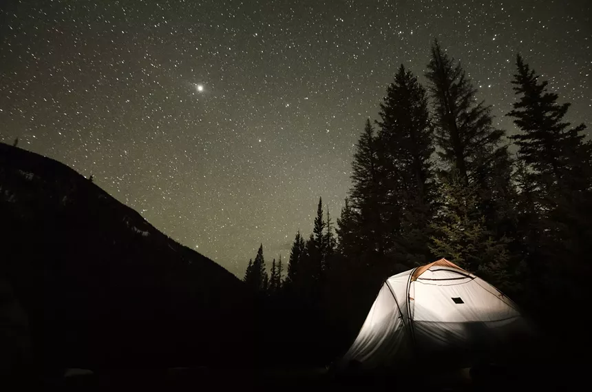 A glowing tent backdropped by a starry night sky in the San Luis Valley
