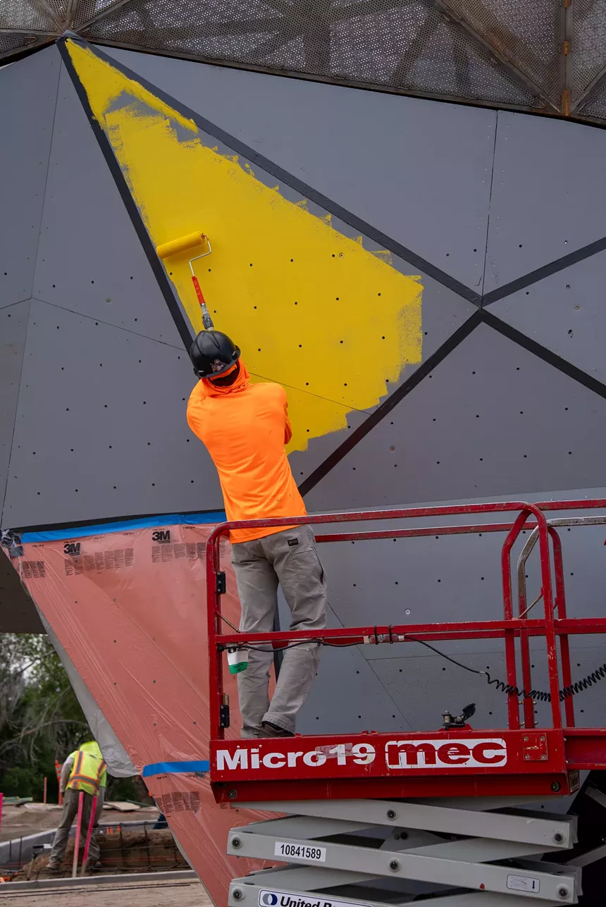 A person paints a panel of the scultpure