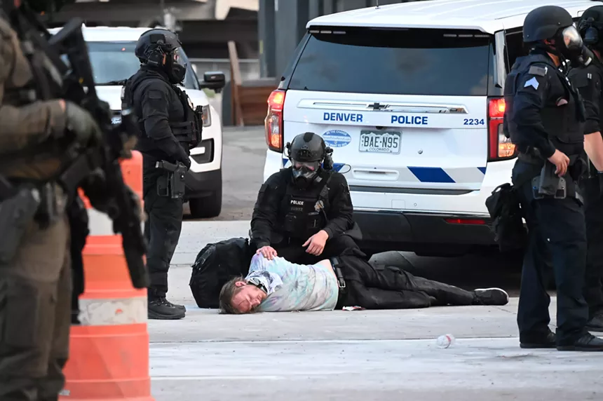A police officer stands over a passed out man.