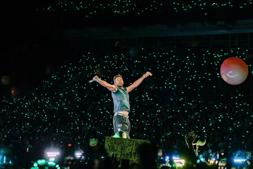 Chris Martin, lead singer of Coldplay, on stage at Empower Field at Mile High embracing the crowd.