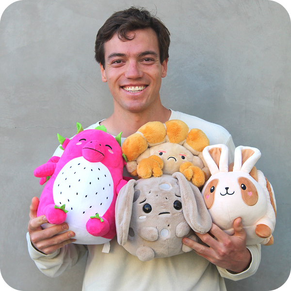 A man holds four plush toys while posing for the camera.