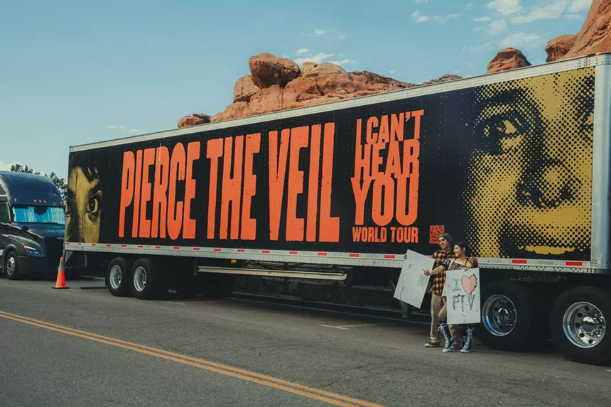 Fans take pictures in front of a Pierce The Veil tour bus.