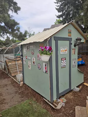 A seafoam green chicken coop that is adorned with images, sayings and flowers.