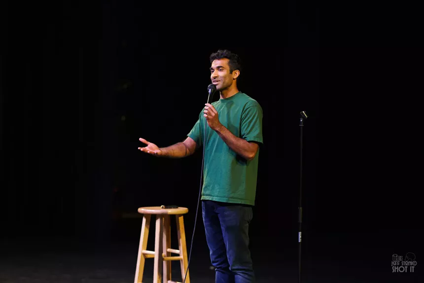A comedian speaks into a microphone onstage.