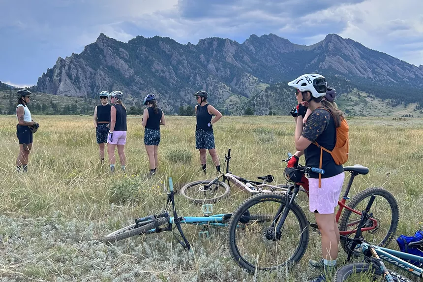 A group of mountain bikers backdropped by the Flatirons