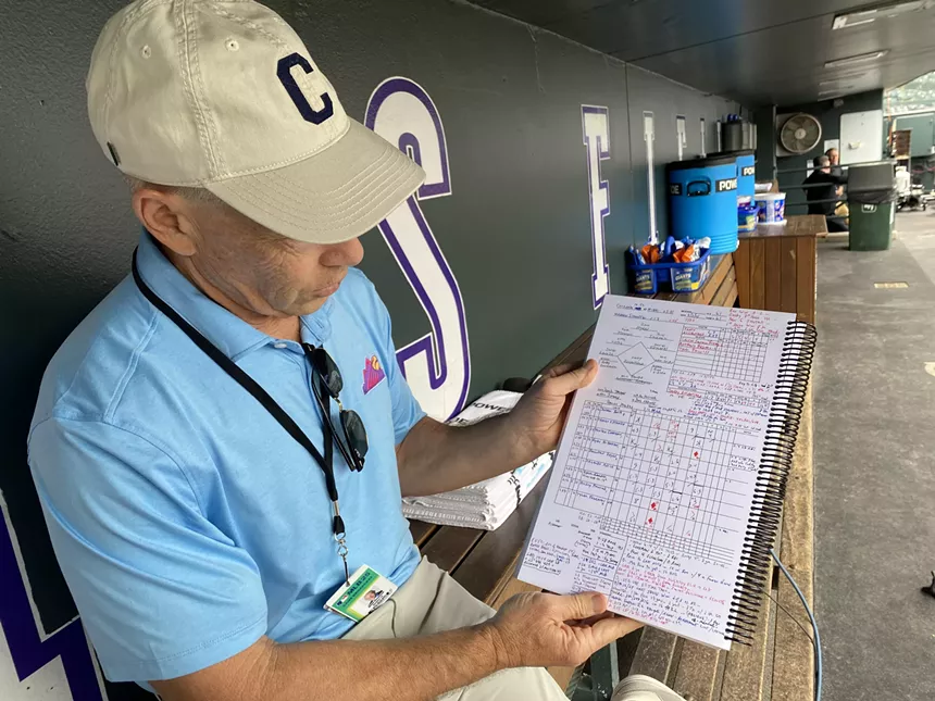 Man shows off baseball scorecard in Rockies dugout
