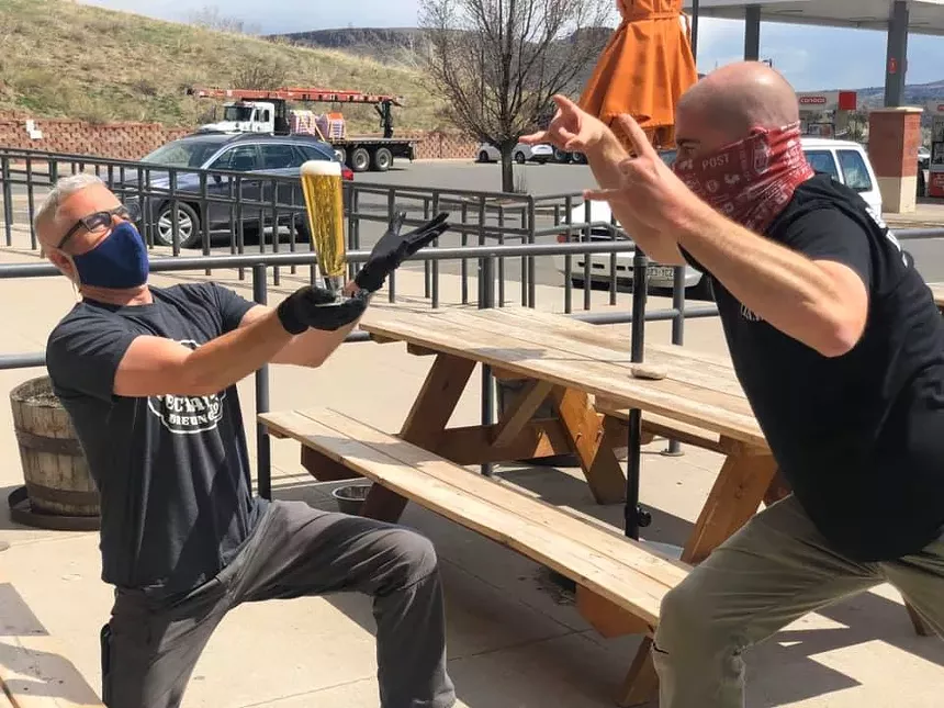People holding beers on patio.