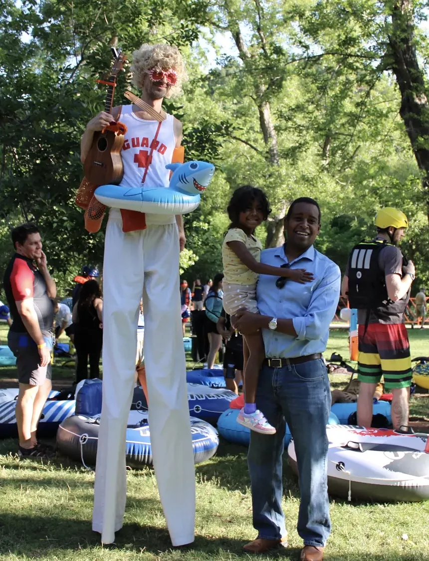 A man on stilts poses with his father and daughter.