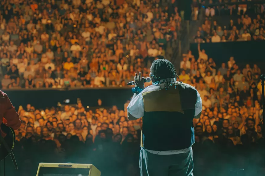 man on stage singing to a large crowd
