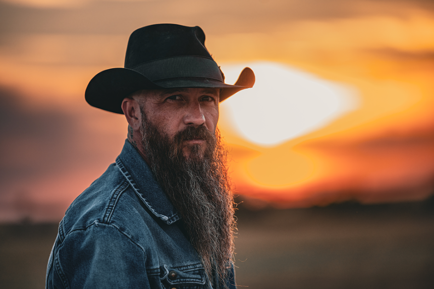 man in cowboy hat in front of a sunset