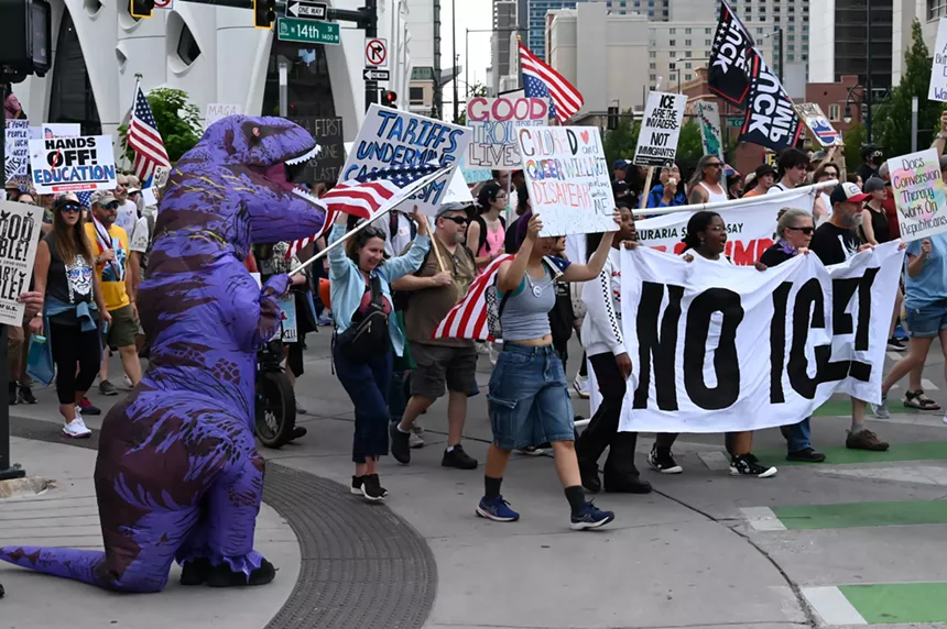 A trex waves the American flag during a march.
