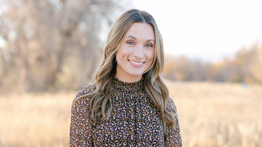 Taelor O'Dorisio smiling to camera while backdropped by an autumn scene