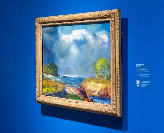 A colorful painting of a landscape against a blue wall