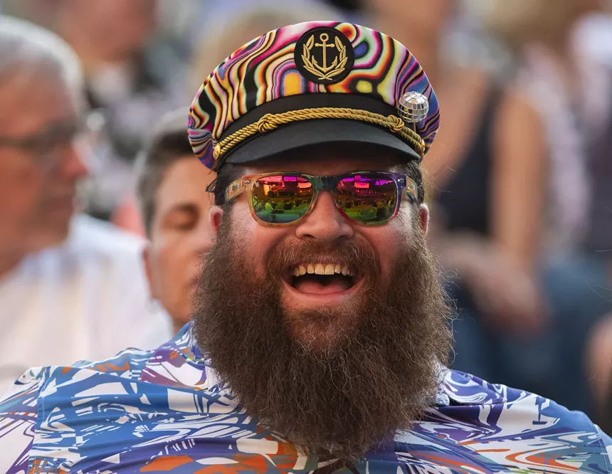 bearded man smiling in a captain hat