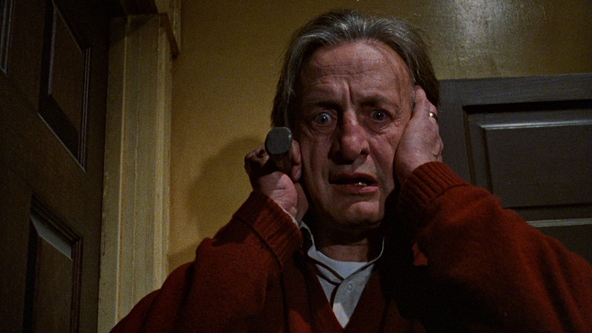 An old man covers his ears