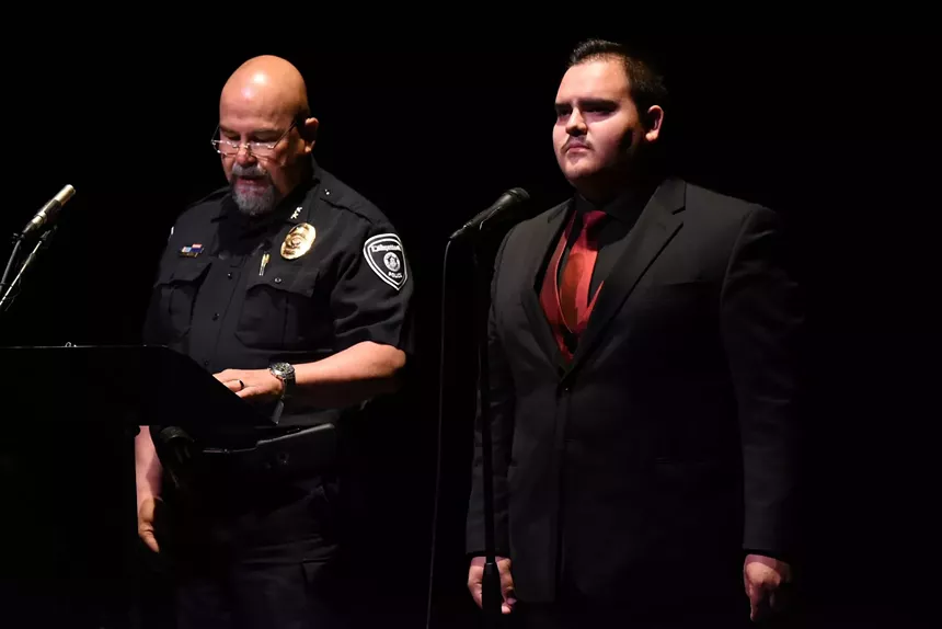 Police officer stands next to man in suit.