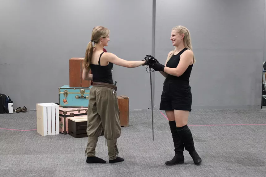 Two woman grasp each others hands.
