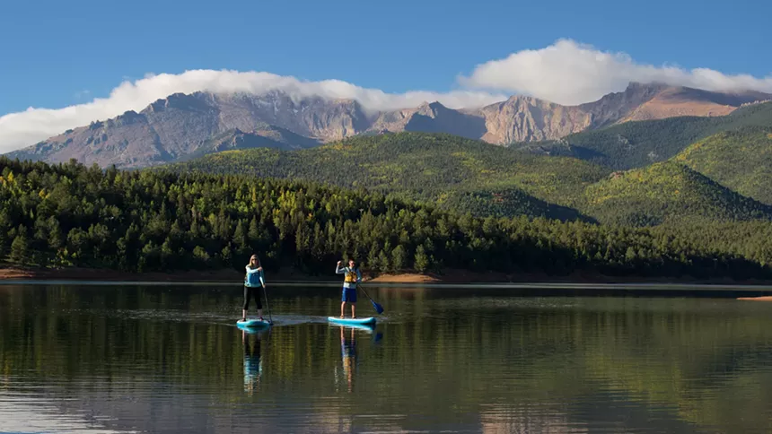 Two people paddleboarding on Crystal Creek Reservoir with Pikes Peak in the background