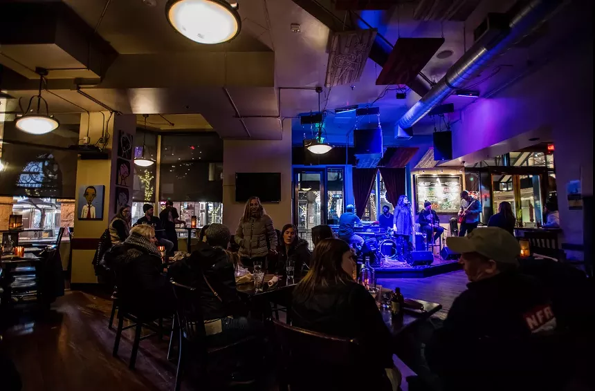 Patrons chat over food and drinks as a local band performs.
