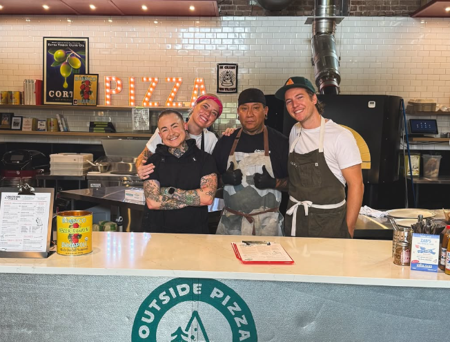 four people posing behind a counter