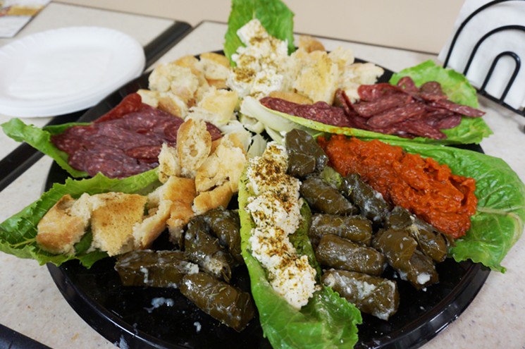 A sampler platter of Balkan foods available at European Market: lukanka sausage, locally baked bread, Bulgarian feta cheese sprinkled with herbs, dolmades and bright orange ajvar. - MARK ANTONATION