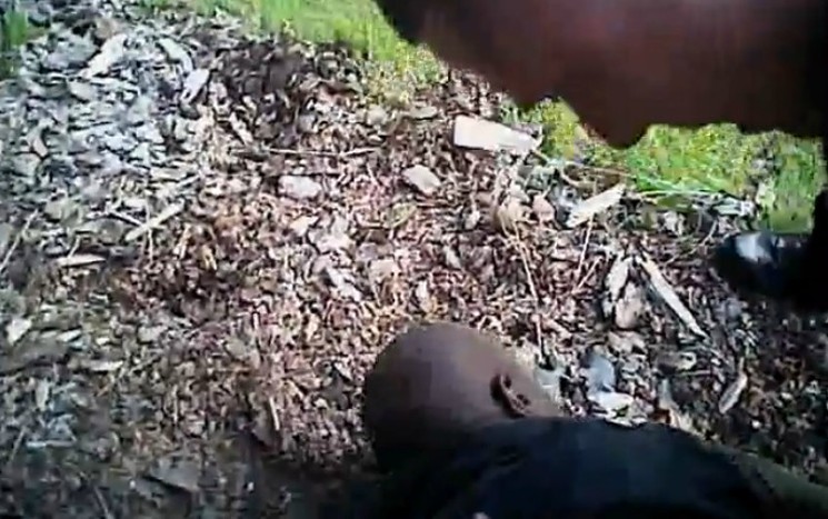 The officer handcuffing Heard, whose face is in the dirt. - COURTESY OF HOLLAND, HOLLAND, EDWARDS & GROSSMAN