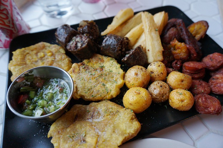 A platter of mixed appetizers, including two kinds of sausage, plantains, yuca and potatoes. - MARK ANTONATION