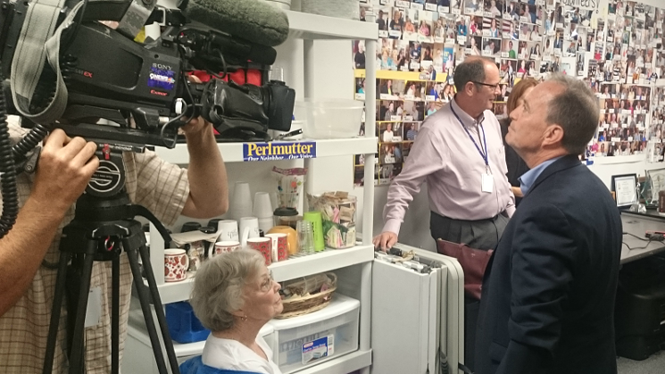 Ed Perlmutter looks at photos on the wall of his campaign office as both a camera operator and his mother look at him. - MICHAEL ROBERTS