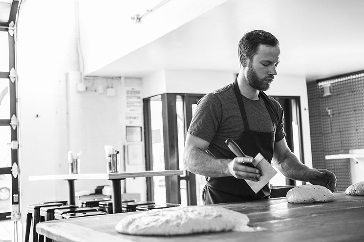 Chef-owner Alex Figura divides seeded sourdough into baking portions. - DANIELLE LIRETTE