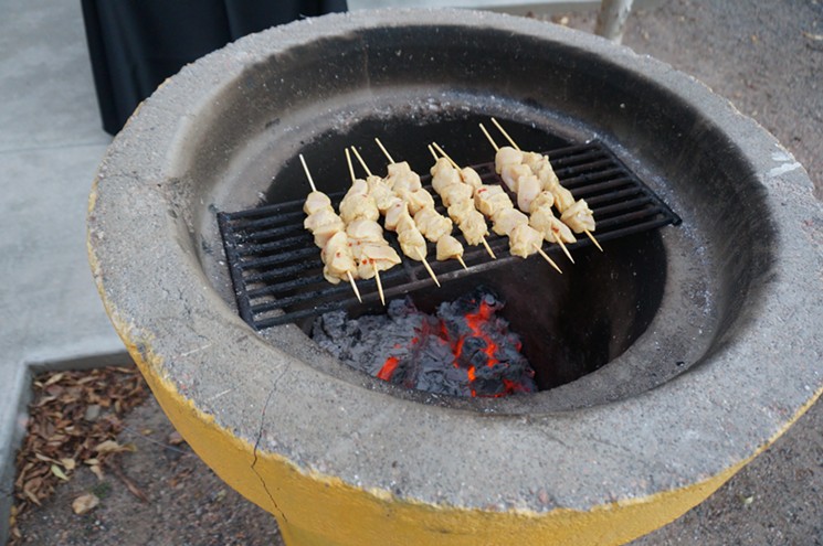 Chicken kabobs cook over hardwood coals on Comal's patio. - MARK ANTONATION