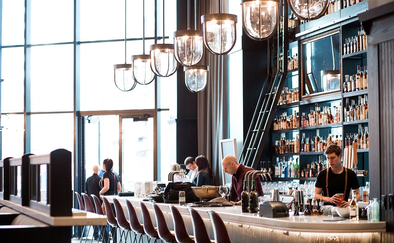 The towering whiskey bar at Hearh & Dram is illuminated by floor-to-ceiling windows at the front of the restaurant.