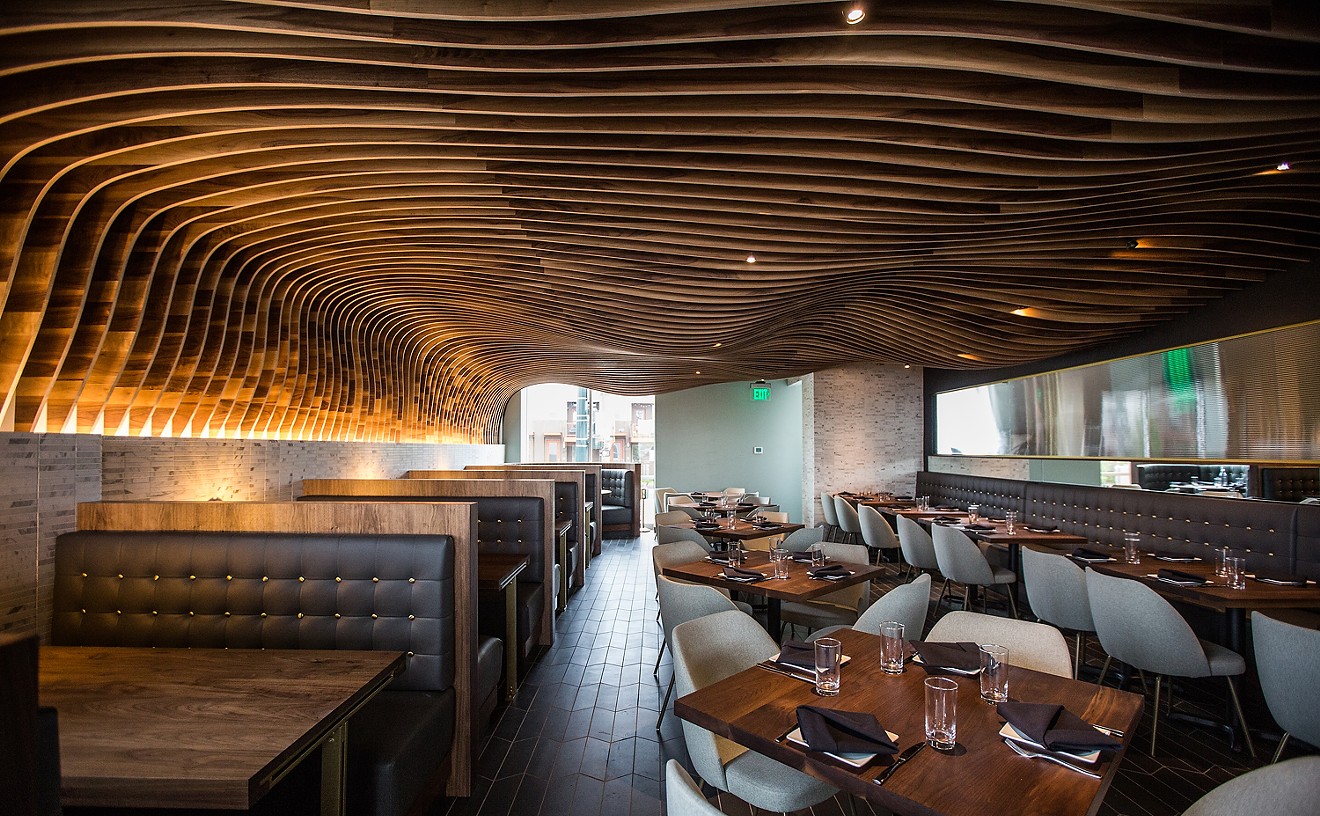 Rippling wood slats form a cavern-like ceiling over the dining room.