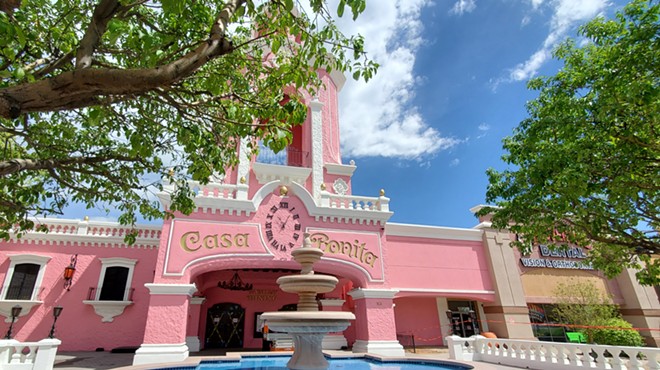 a fountain in front of a pink building