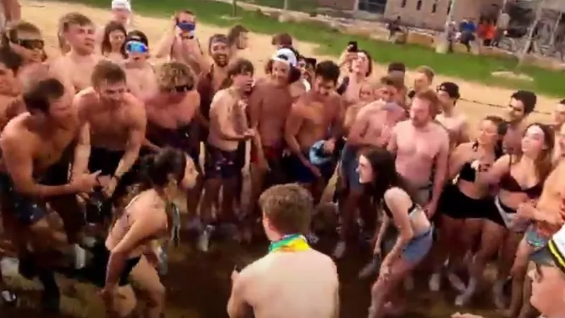 Image: A group of unmasked students gather to watch a pair of young women wrestle during the May 1 CSU Undie Run.