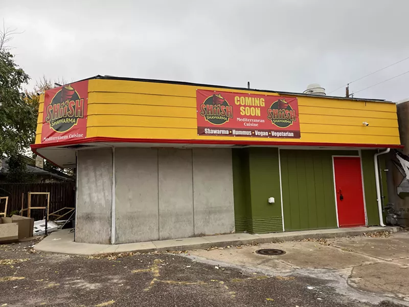 Image: a green and yellow building with a "coming soon" sign hanging on it