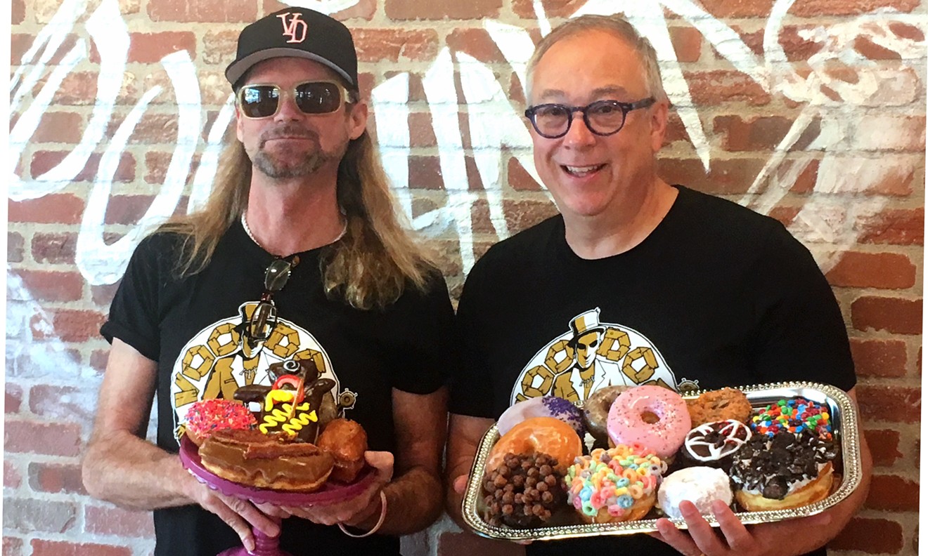 Tres Shannon (left) and Kenneth "Cat Daddy" Pogson bask in the pink glow of their new Voodoo Doughnut.