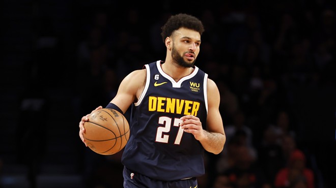 Jamal Murray wears a navy blue Nugget jersey with yellow lettering while dribbling an orange basketball.