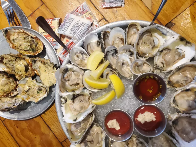 Image: a platter of raw oysters next to grilled oysters on a plate