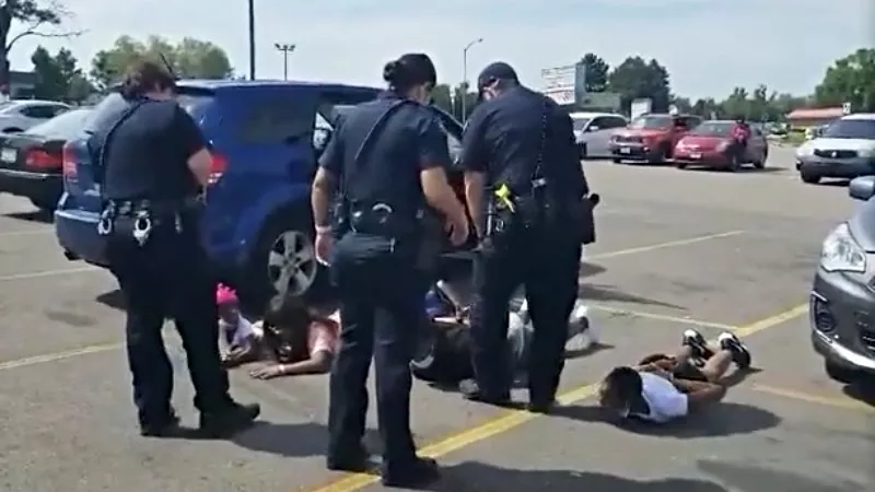 Image: A witness video shows members of Brittney Gilliam's family lying down in a parking lot under orders from Aurora police officers.