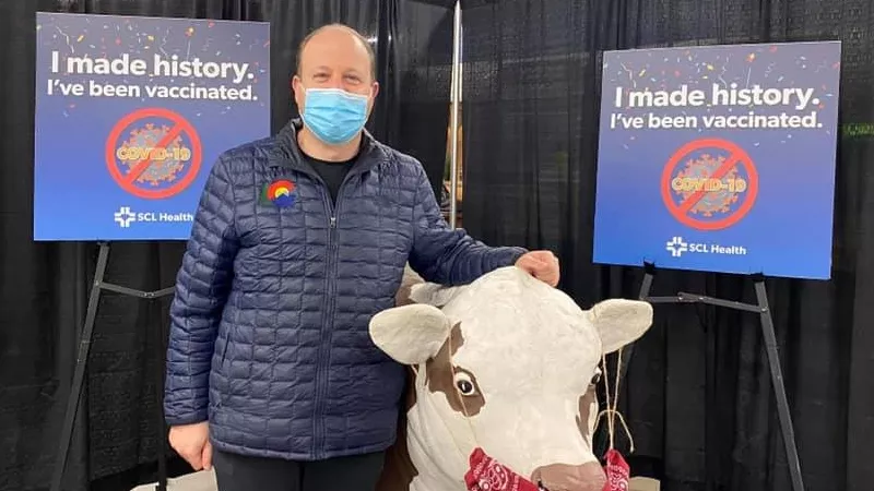 Image: Governor Jared Polis and a masked bovine at an SCL Health vaccination event at the National Western Complex on February 6.