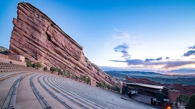 A sunrise view of the stage, empty stands and massive rock formation at Red Rocks Amphitheatre